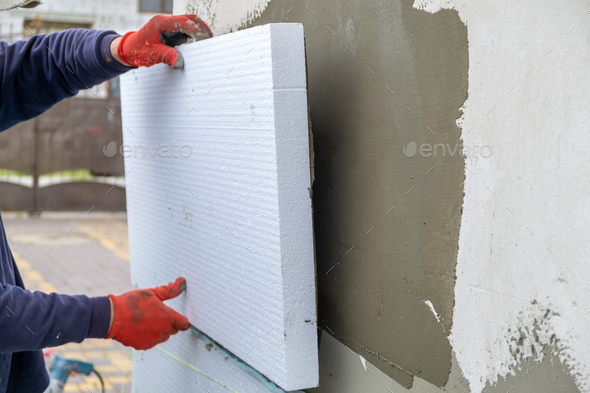 Insulation of the house with polyfoam. The worker is installing a
