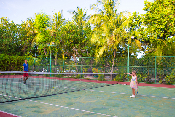 Little girl playing tennis with her dad on the court Stock Photo by ...