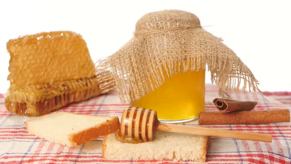 Honey Spoon Dripper and Jar with Stick Pouring Over Toast Bread, Honeycomb on White alt