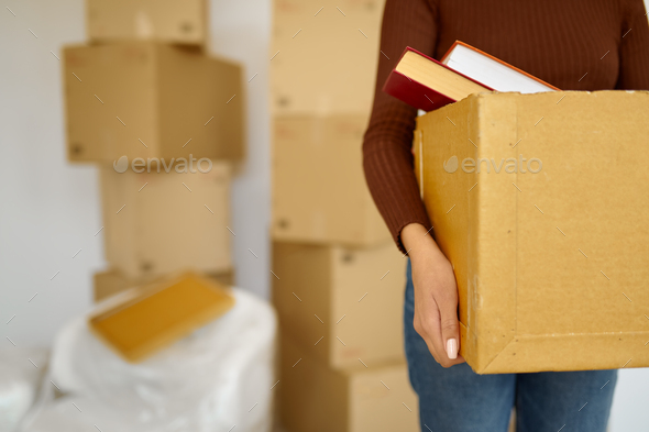 Young woman carrying cardboard box during relocation