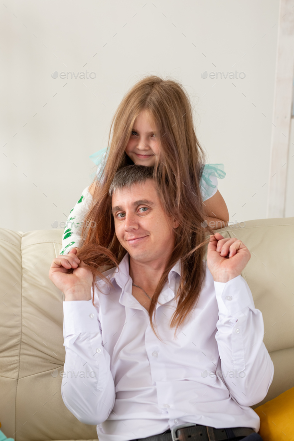Father and his daughter having fun in their living room. Little girl have injury hand but she is