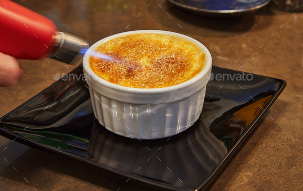 Creme brulee with mushrooms in special form, the chef burns sugar with burner