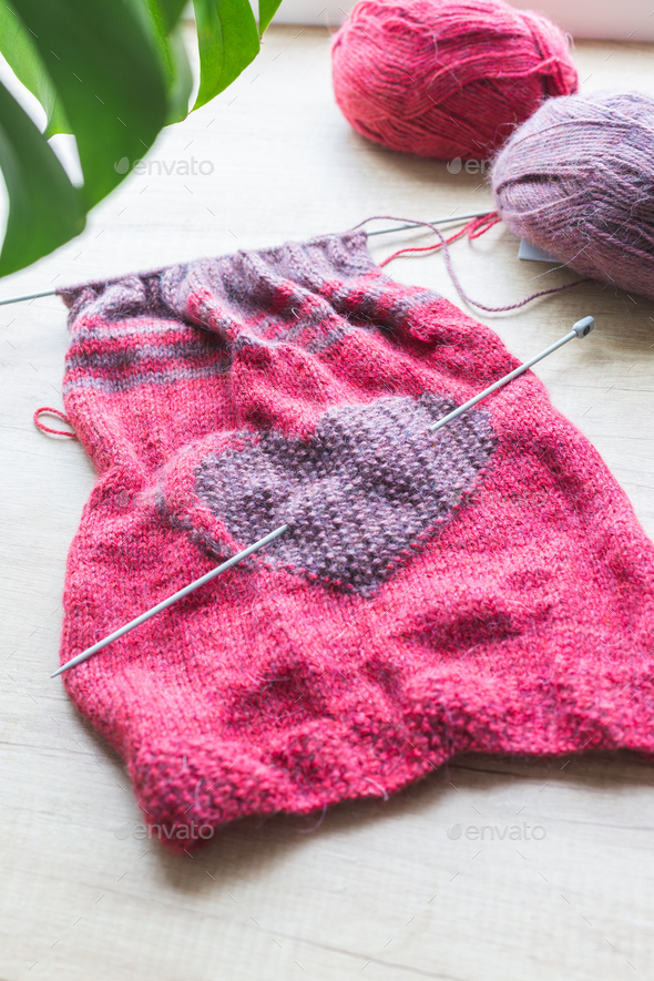 On a light background are clews of wool thread and hand knitting with a heart. - Stock Photo - Images