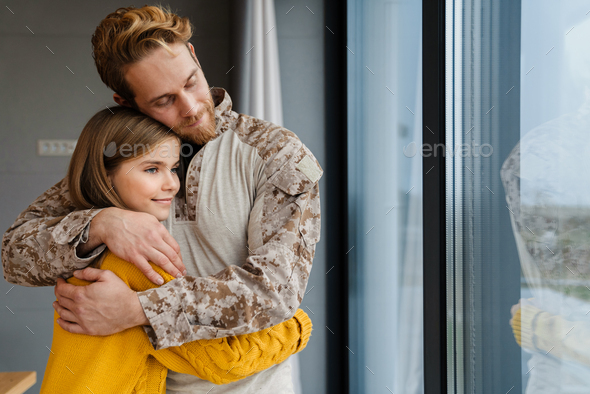 Happy military man smiling while hugging her daughter in his hands