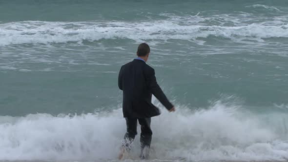 Male walking into ocean in suit alt