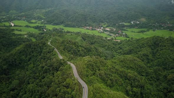 Aerial view flying above lush green tropical rain forest mountain with rain cloud cover during the r alt