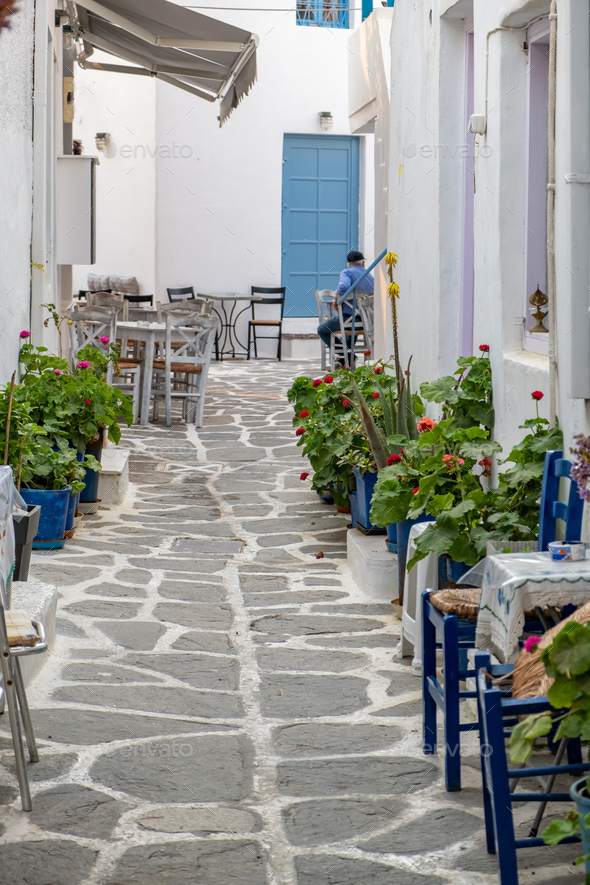 Paros island Naousa Greece. Building cobblestone alley outdoor cafe tavern summer day. Vertical