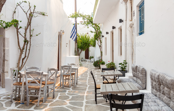 Paros island Naousa Greece. Building plant cobblestone alley outdoor cafe tavern summer day.