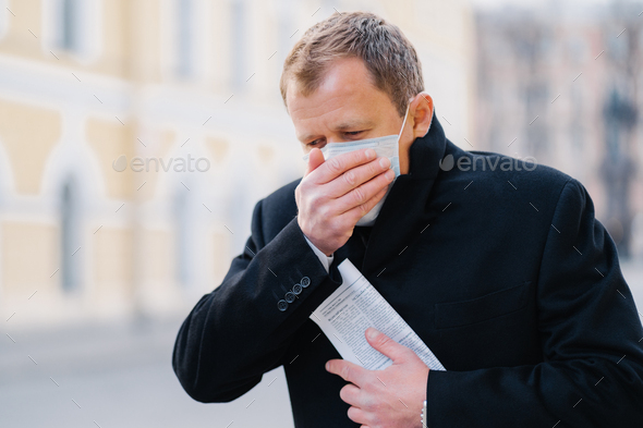 Sick man coughs, covers mouth with palm, wears medical mask, has symptoms of allergy