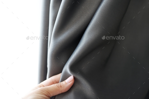 Woman\'s hand touching curtain, gray blackout fabric, light-blocking fabric