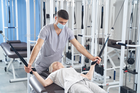 Lying woman training arms with cable machine Stock Photo by Iakobchuk