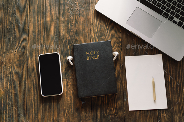 Church online Sunday new normal concept. Bible, cell phone and earbuds on a wood background.