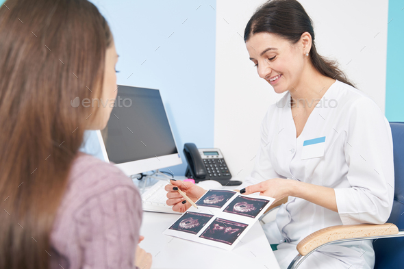 Joyous doctor showing first trimester fetal ultrasound images to woman