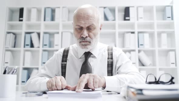 Senior business executive checking a contract with a magnifier