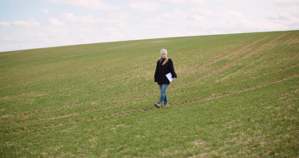 Agriculture - Female Farmer Walking on Agricultural Field alt