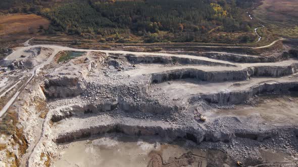Aerial view of Slope operating granite quarry with mining equipment on ledges alt