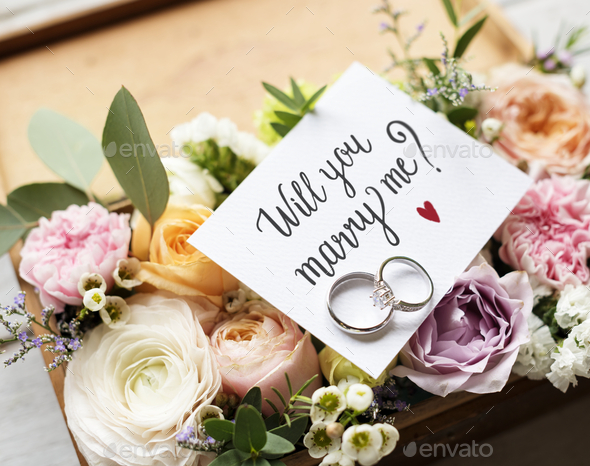A Surprise Marriage Proposal with Will You Marry Me Card and Rings on Flowers Bouquet Present Love
