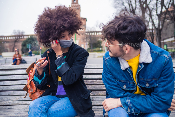 Couple multiethnic friends wearing medical mask having conversation