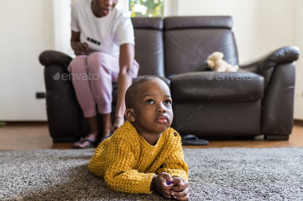 male toddler indoor at home lying carpet watching tv