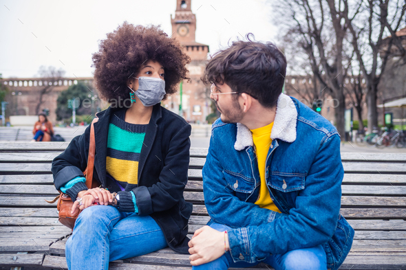 Couple multiethnic friends wearing medical mask having conversation