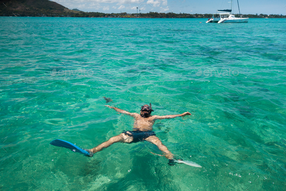 A guy in fins and a mask swims in a lagoon on the island of Mauritius
