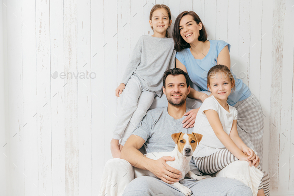 Happy family indoor. Handsome father holds dog, beautiful brunette mother and two daughters
