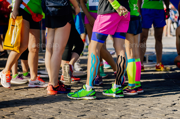 legs female runners with kinesio tape and compression socks