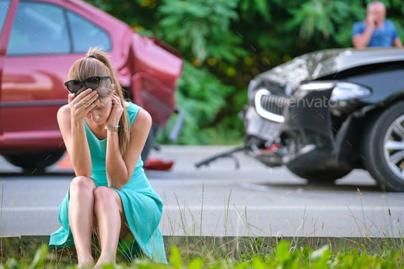 Stressed woman driver sitting on street side shocked after car accident. Road safety and insurance