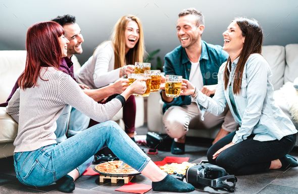 Young friends toasting beer at home party after college lessons