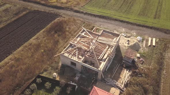 Top Down Aerial View of Two Private Houses One Under Construction with Wooden Roofing Frame and alt