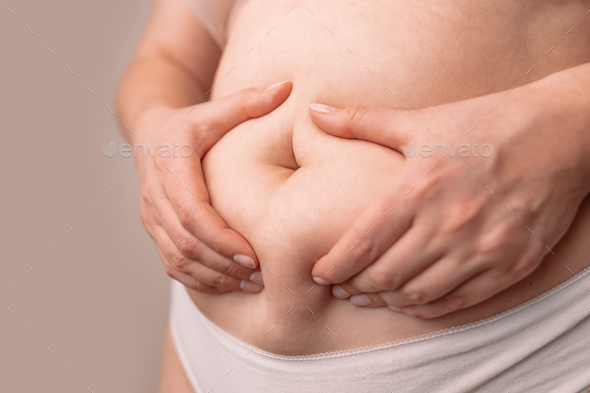 Fat female belly, woman holding skin to check cellulite