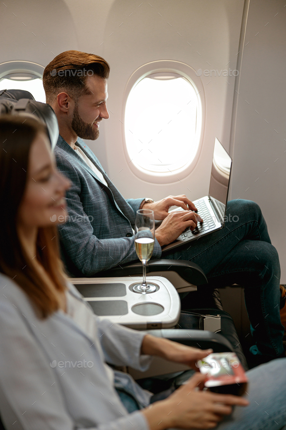 Bearded man using modern laptop in airplane