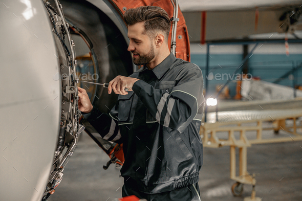 Male aviation mechanic repairing aircraft in hangar Stock Photo by ...