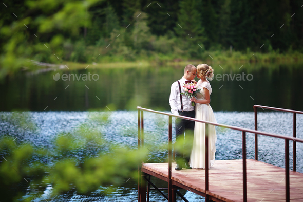 Beautiful young wedding couple, bride and groom posing on lake background. The groom and the bride - Stock Photo - Images