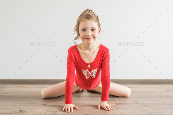 Flexible little girl in red leotard doing gymnastic Stock Photo by
