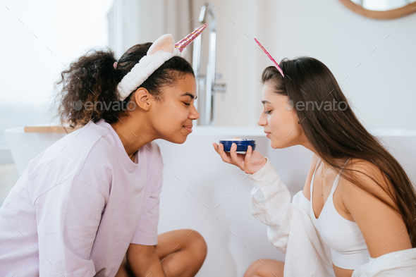 Two girls in the bath playing with face cream - Stock Photo - Images