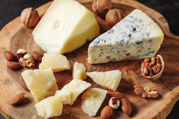 Tasting cheese plate with parmesan, gorgonzola, sheep milk cheese, almonds, nuts on a wooden board