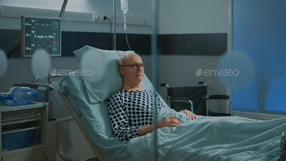 Sick old man staying in hospital ward bed with oximeter