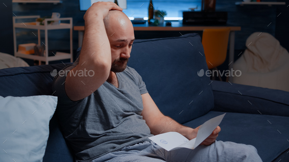 Worried anxious young man reading bad message in postal letter
