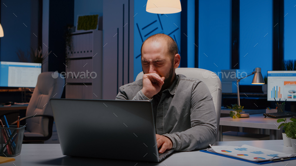 Exhausted sleppy businessman yawning while working at management project deadline