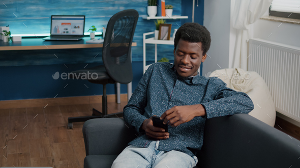 African american man with phone in hands looking at online streaming services content