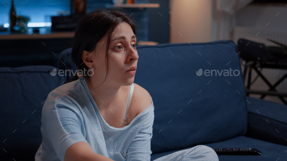 Sensitive woman watching drama movie on tv crying sitting on sofa