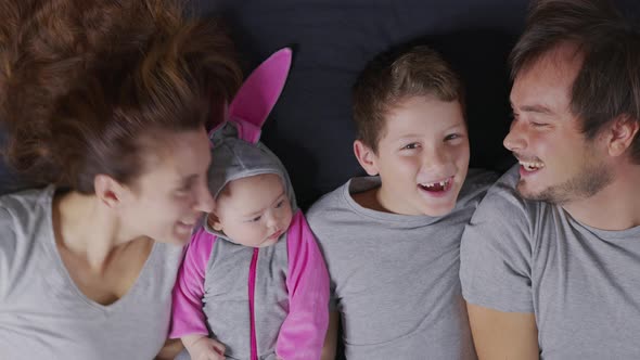 Young Mother and Father Kiss Their Children. Portrait of Happy Family. View From Above. alt