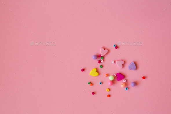 Beaded and heart-shaped beads are scattered on a pink background. Stock