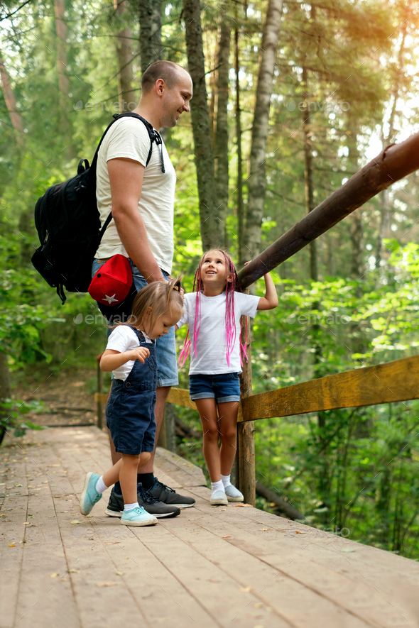 A father and his daughters are walking along ecological trails in a forest area