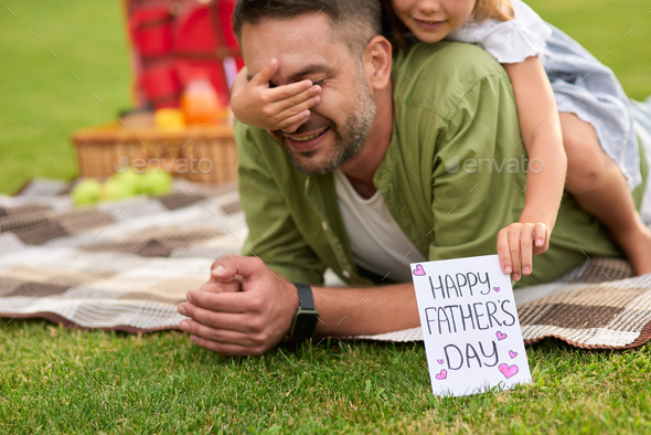 Cute little girl surprising her father, greeting and giving him handmade postcard, daddy and