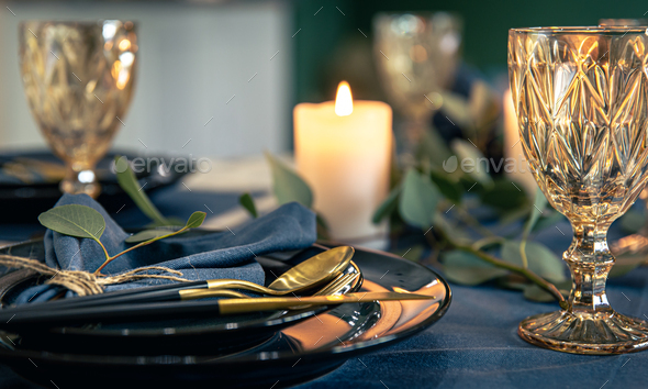 Table setting with textured wine glasses, candles and leaves. Stock Photo  by puhimec