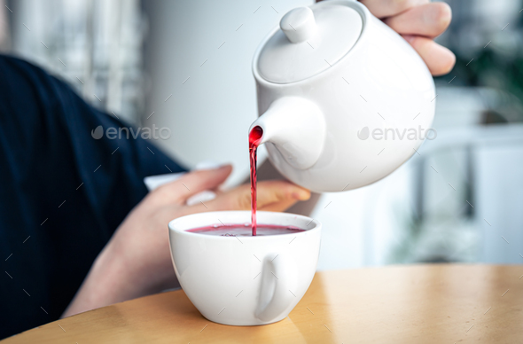 teapot pouring tea into flying cups, on white background Stock