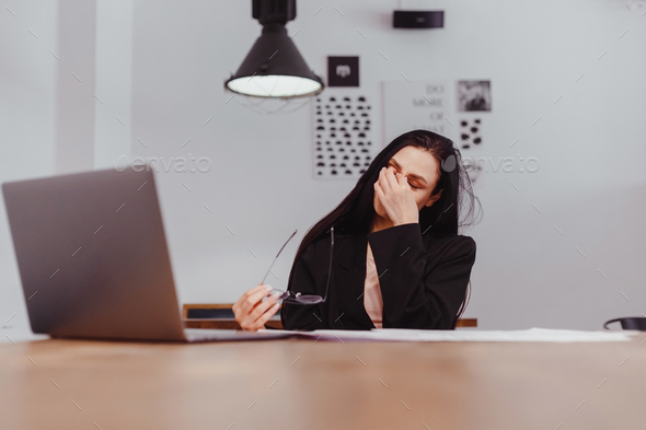 Woman taking off glasses tired of computer work, suffering from long laptop use, eyes fatigue