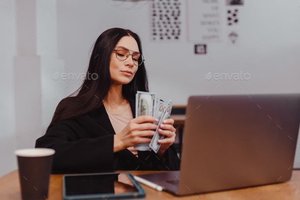 excited business woman count money at laptop dreaming about planning purchases